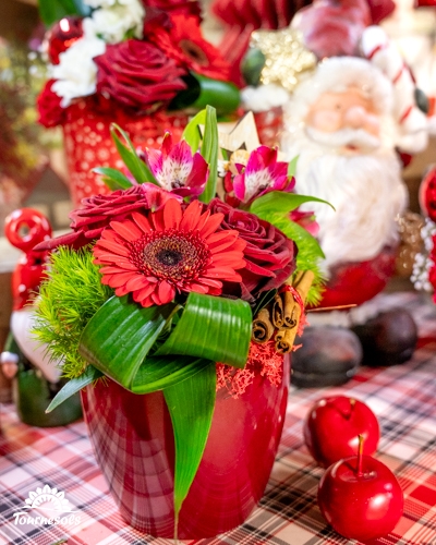 Bouquet de fleurs rouges dans un vase rouge avec décorations de Noël.